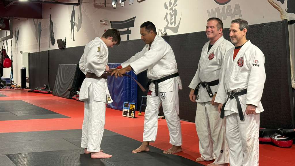 Daniel getting his brown belt tied around him as he gets promoted in judo